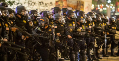 Police officers stand in a row while wearing riot gear.