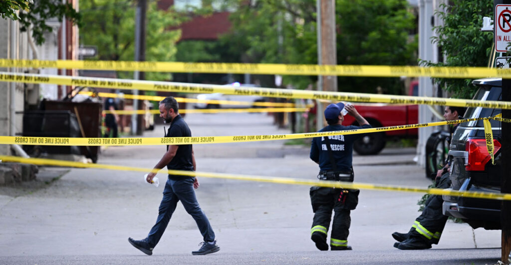 Police walk behind yellow tape at the scene of Sunday's terrorist attack in Boulder, Colorado.