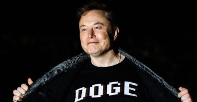 Elon Musk walks to the White House wearing a DOGE shirt.