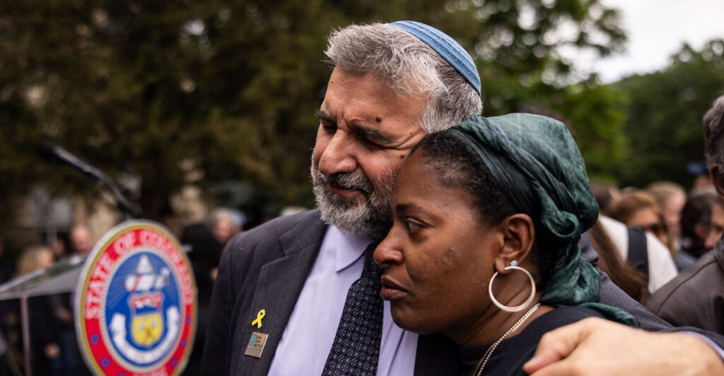 Marc Soloway puts his left arm around a woman as he had a pained looked on his face.