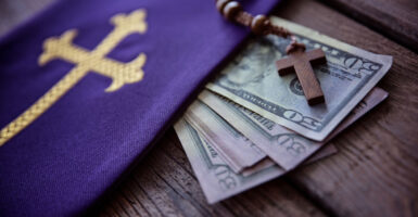 A rosary, a purple cloth with gold cross and a stack of $50 bills.