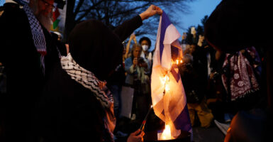 Protesters in Washington, D.C., burn an Israeli flag at night.