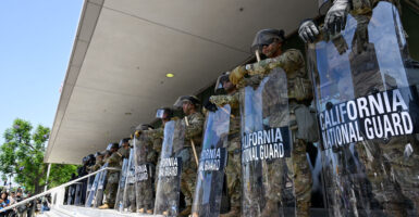 Police and California National Guardsmen stand guard as thousands of anti-ICE protesters are gathered outside of a federal building in Los Angeles on Monday.