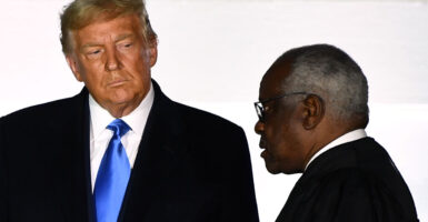 President Donald Trump looks at Supreme Court Justice Clarence Thomas, who is in profile.