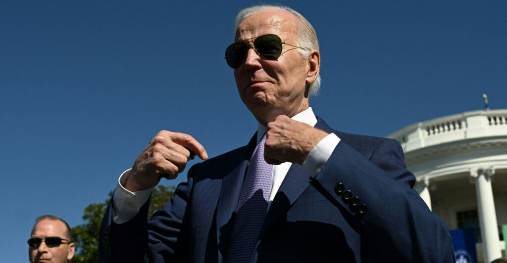 Joe Biden in aviator glasses point to himself during an event outside the White House.