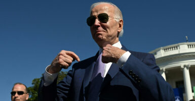 Joe Biden in aviator glasses point to himself during an event outside the White House.