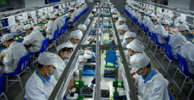 Dozens of workers clad in white frocks and hats work on pods for e-cigarettes at a Chinese factory.