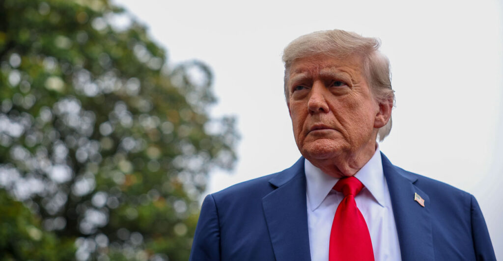 A low angle bust of Donald Trump outdoors.