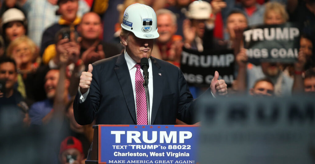 Donald Trump in a hard hat, giving two thumbs up at 2016 rally with coal workers.