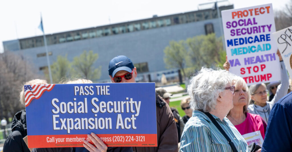 A group of seniors at a rally in support of Social Security. Sign in front reads "Pass the Social Security Expansion Act."