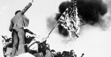 Black-and-white photo of Iranians burning an American flag in the days after Iran took dozens of Americans hostage.