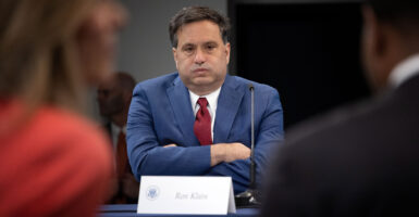Ron Klain, chief of staff for Joe Biden, sits with arms folded at a meeting, his cheeks puffed out as if letting out a big exhale.