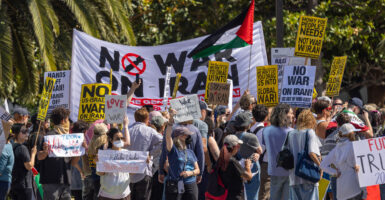 Protesters in Los Angeles carry banner reading "No War on Iran," as others carry signs reading "We won't let you drag us into global war." One protester waves an Iranian flag.