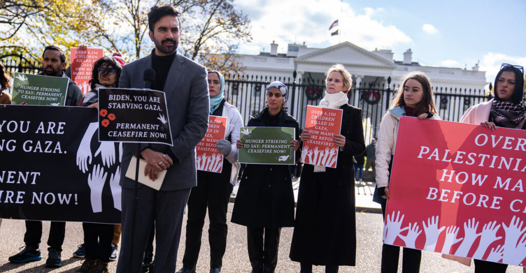 Zohran Mamdani speaking at a 2023 pro-Gaza, anti-Biden protest in front of White House. A group of people are behind him, including actress Cynthia Nixon.