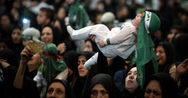 An Iranian woman holds her young child aloft in a crowd in Tehran on Oct. 7, 2016.