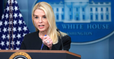 Attorney General Pam Bondi, in a black suit, presses her pen into the podium to make a point during a White House briefing.