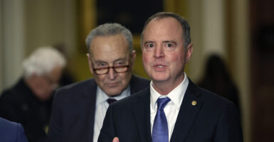 Adam Schiff in a black suit with Chuck Schumer behind him