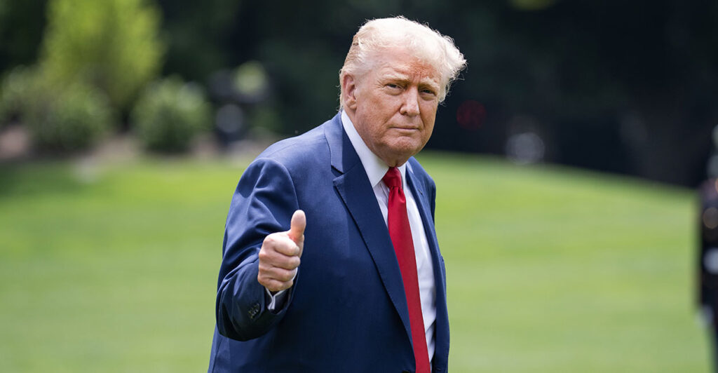 Donald Trump in a blue suit making a thumb's up