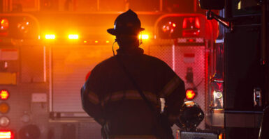 the silhouette of a firefighter in front of the lights of a fire truck on the scene