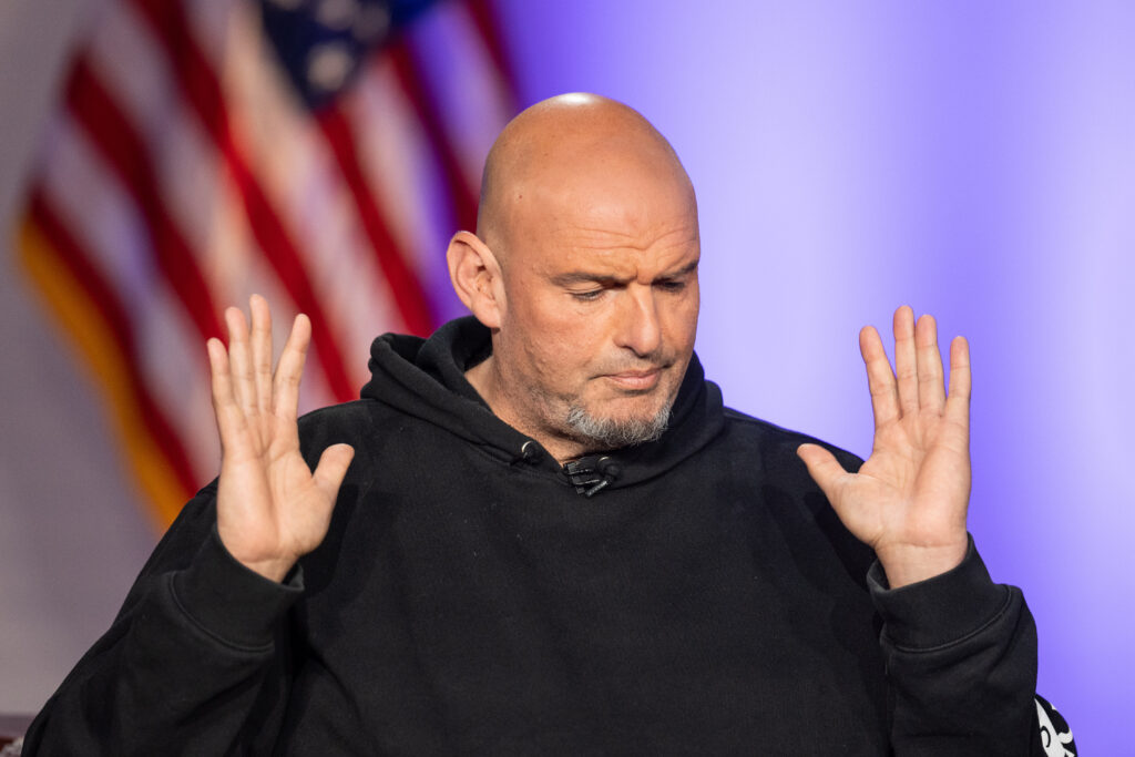Sen. John Fetterman, D-Pa., with this hands raised and a U.S. flag behind him