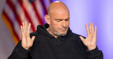 Sen. John Fetterman, D-Pa., with this hands raised and a U.S. flag behind him