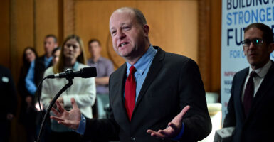 Jared Polis in a black and red suit