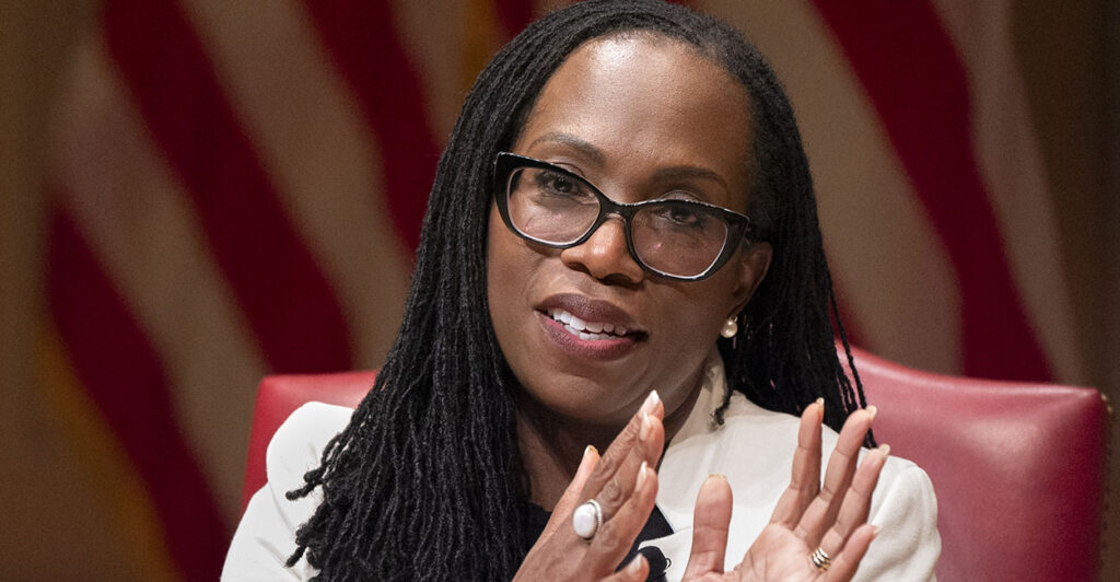 Ketanji Brown Jackson in a cream suit in front of an American flag