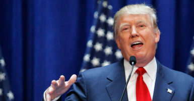 Donald Trump announcing his presidential candidacy in 2015, with American flags as a backdrop.