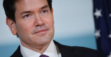 Marco Rubio gazes to the side of the camera. He wears a suit and purple tie.