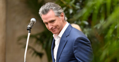 California Gov. Gavin Newson in a blue suit and white shirt, looks down.