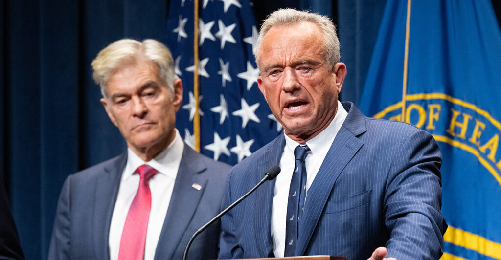 Dr. Mehmet Oz watches HHS Secretary Robert F. Kennedy Jr. speak at a press conference.
