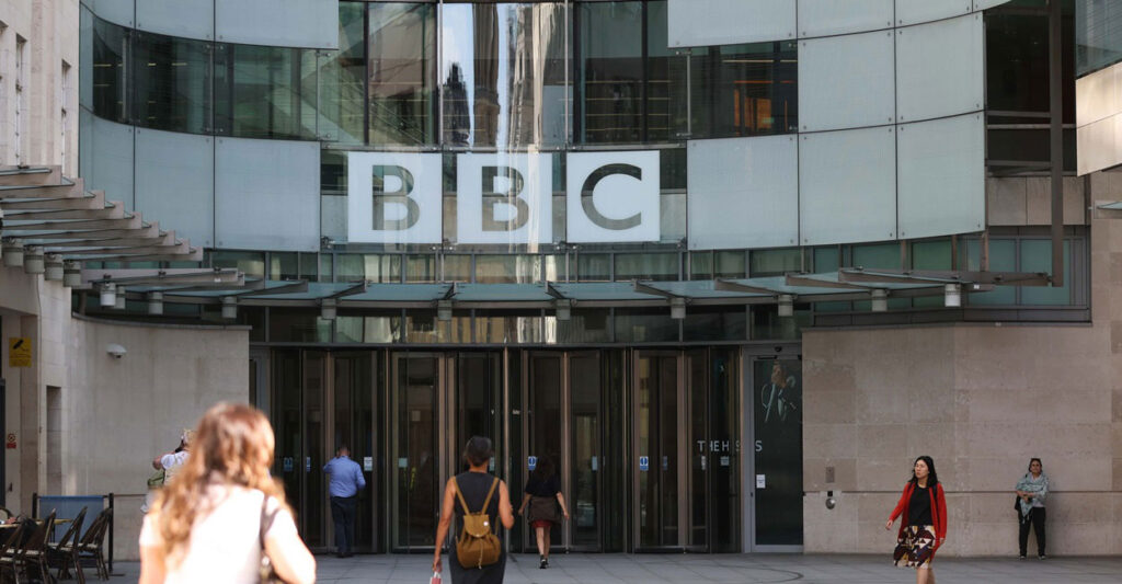 The BBC sign hangs is in the glass window of the company's headquarters.