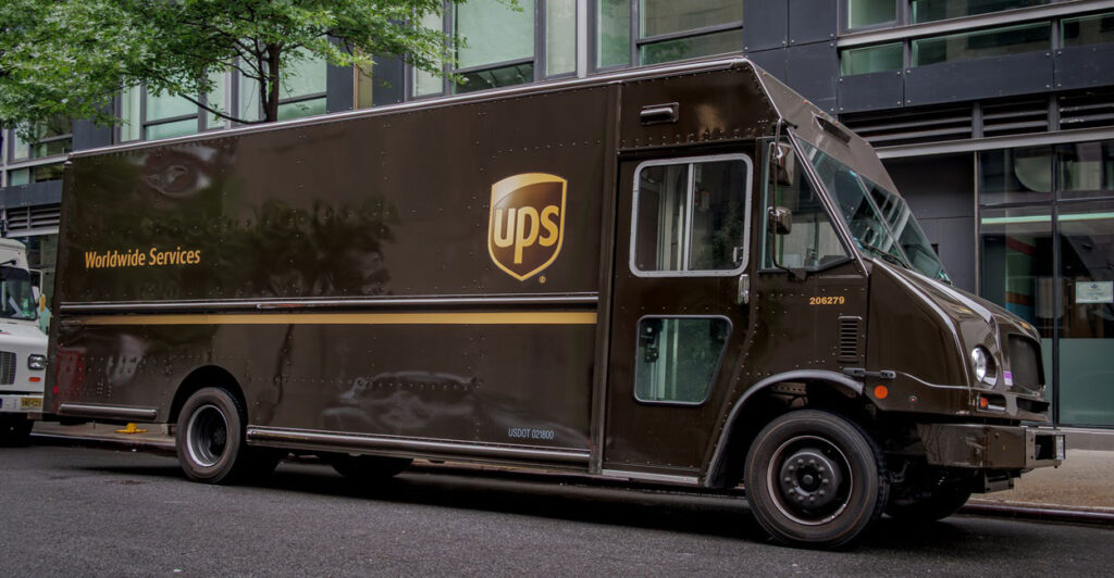 A brown UPS truck is parked on the street in front of a building.