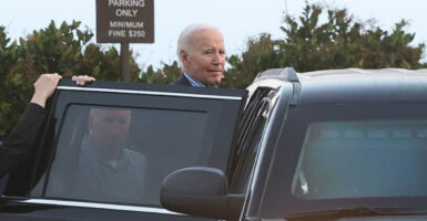 Joe Biden is entering the back seat of a luxury vehicle.