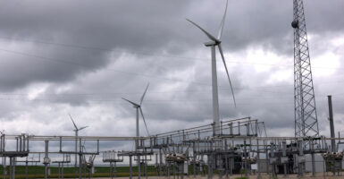Large wind turbines dominate the skyline on a cloudy day in Iowa.