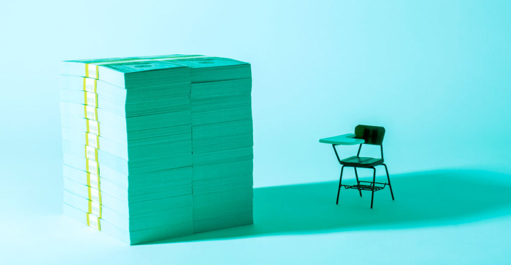 A graphic illustration of a tiny classroom desk next to huge stack of dollar bills