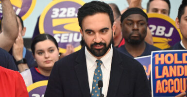 New York mayoral candidate Zohran Mamdani backed by grim SEIU sign-carrying supporters, gives a speech.