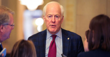 Sen. John Cornyn, R-Texas, faces the camera while reporters face him and ask questions.