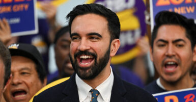 Zohran Mamdani, backed by union supporters, laughs.