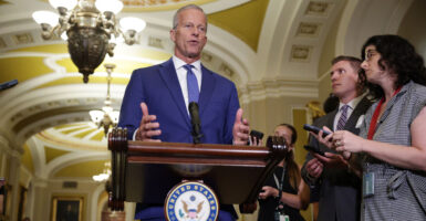 Senate Majority Leader John Thune speaks behind a podium to reporters.