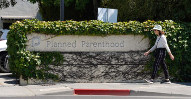 A woman in a hat walks passed a Planned Parenthood sign.