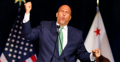 Sen. Cory Booker, with eyes closed, one fist raised, the other pointed down, emotes while speaking at California Democratic Party Convention.