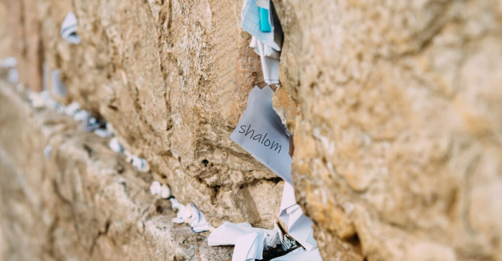 A note reading "Shalom"—Hebrew for "Peace"—sticks out of the Western Wall in Jerusalem, along with many other notes.