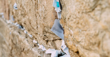 A note reading "Shalom"—Hebrew for "Peace"—sticks out of the Western Wall in Jerusalem, along with many other notes.
