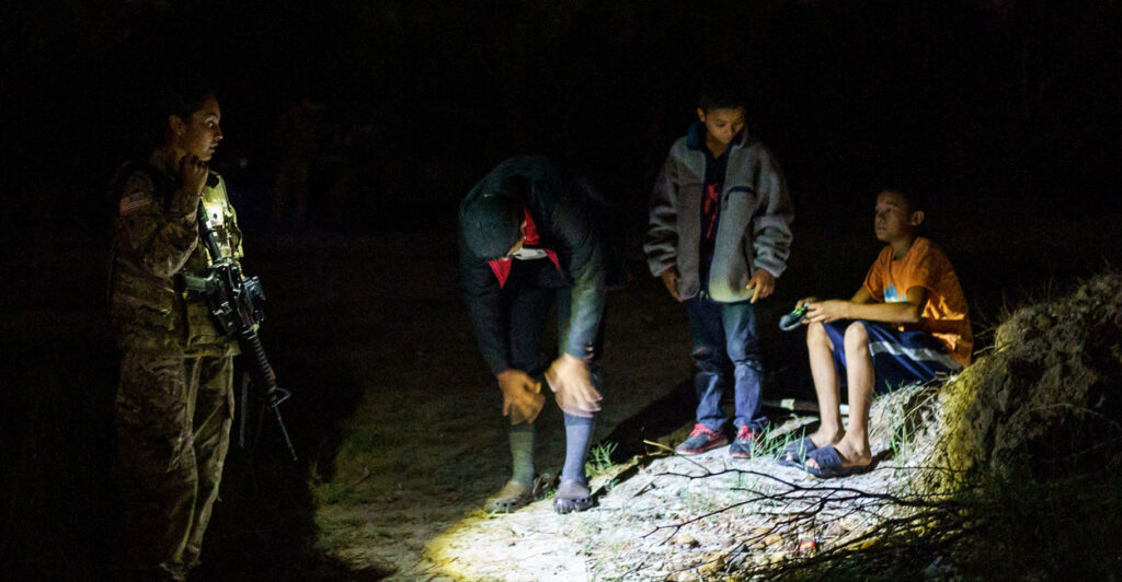 A National Guardswoman speaks to three unaccompanied children at night on the banks of the Rio Grande in Roma, Texas, on July 9, 2021.