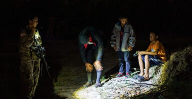 A National Guardswoman speaks to three unaccompanied children at night on the banks of the Rio Grande in Roma, Texas, on July 9, 2021.