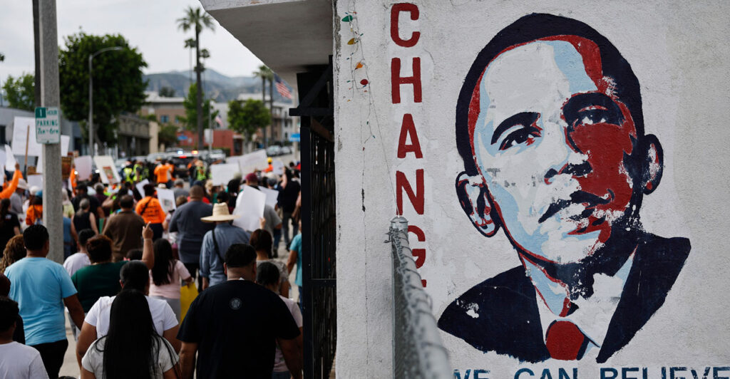 An Obama "Change" poster with his portrait hangs on a busy street.