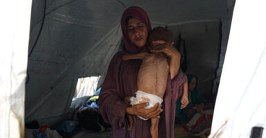 A Palestinian woman holds her 18-month-old emaciated-looking child.