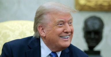 A smiling Donald Trump in the Oval Office.