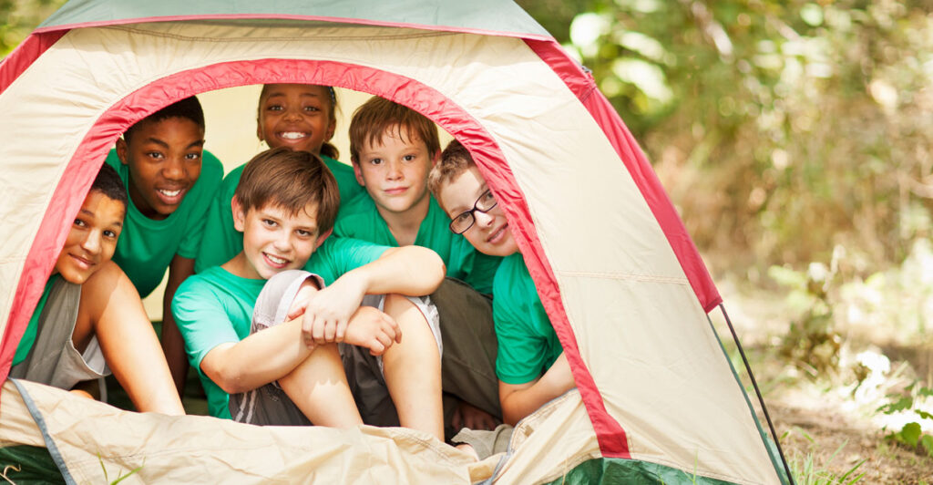 Children in a tent smile at the camera.